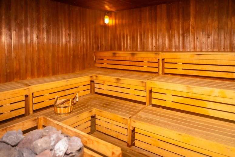 Interior de una sauna con banco, piedras y cubo, sin personas, en un complejo turístico de lujo.
